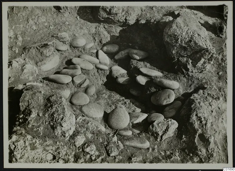 Smooth oval stones set in a curving arrangement among rock outcrops during excavation at Petra tou Limniti.