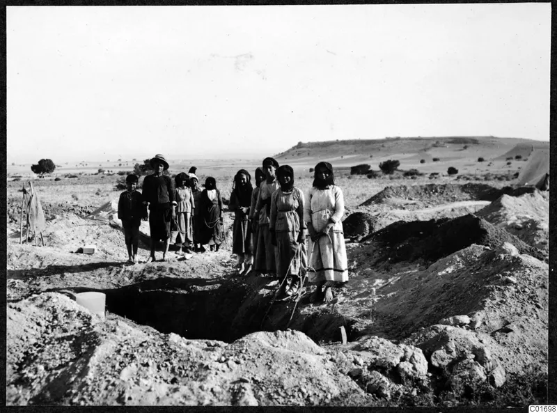 Women, a man and a child standing beside an excavated dromos at Ayios Iakovos