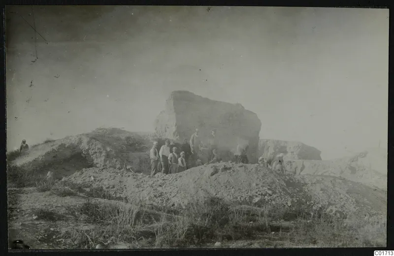Bamboula cliff from the south during demolition, with a group of men standing in front of the rock face