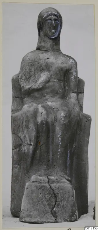 Seated terracotta figure on a rectangular base, with a high-backed seat and cracks across its grey surface.