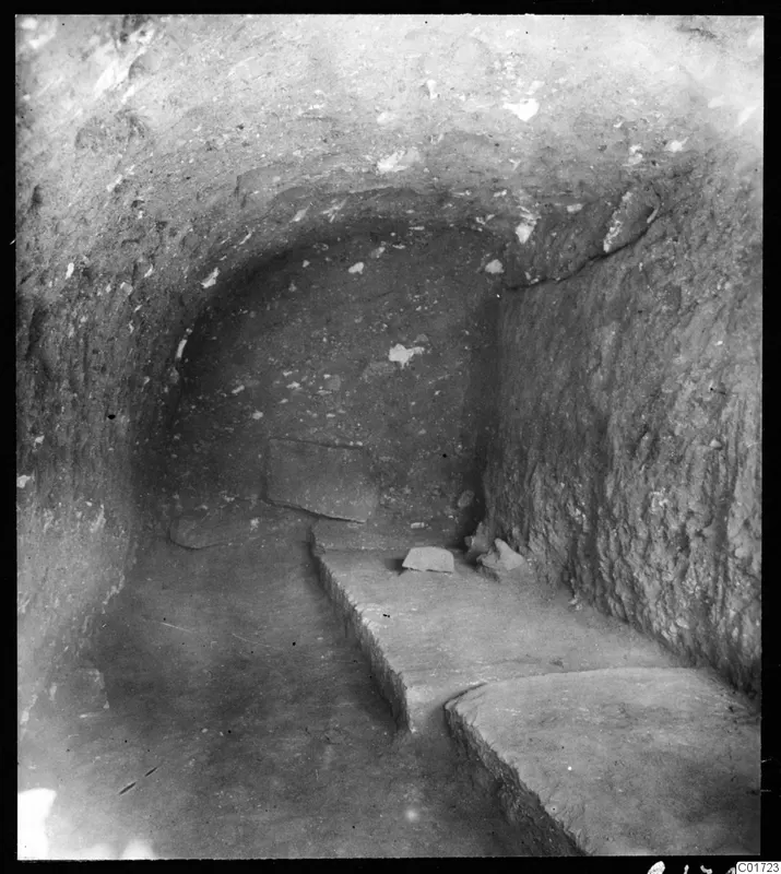 Excavated gallery at Kition with a rounded earth ceiling and flat stone slabs along one side