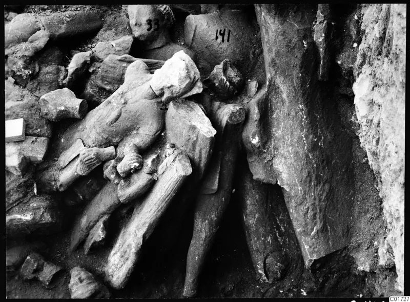Excavated stone sculpture fragments lying jumbled in soil in the cult room, large depot, Kition