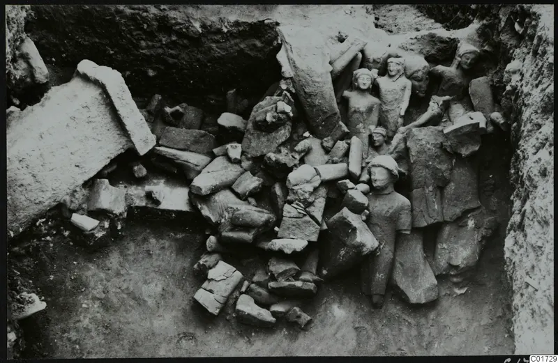 Excavation of the cult room great deposit at Kition, showing a heap of large broken stone sculptures in a trench