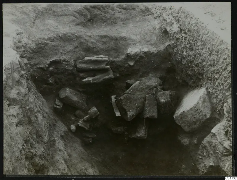 Excavation pit at Kition with broken stone pieces lying in situ among soil and rock.