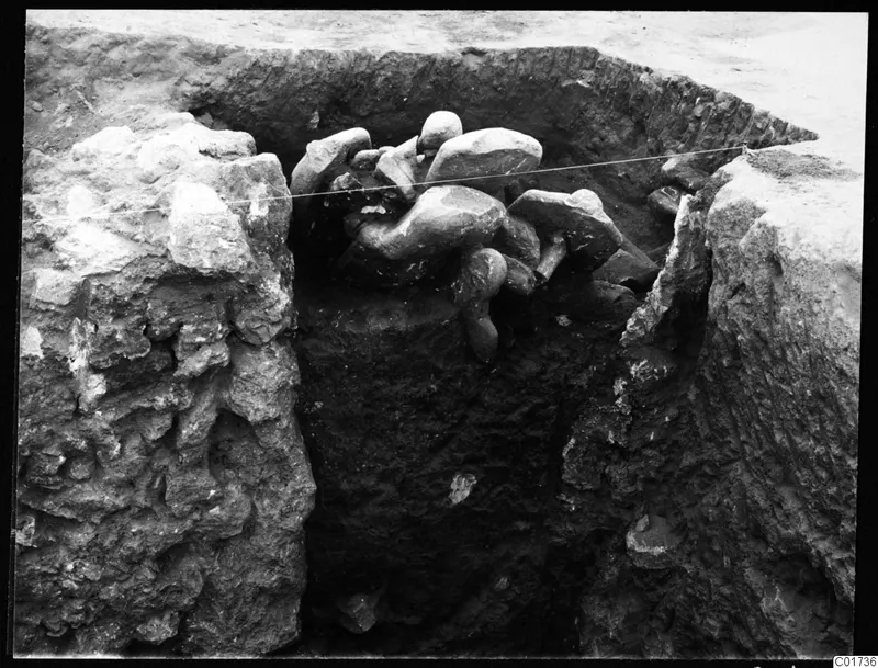 Central pit at Kition with sculpture fragments lying in situ among stones, a taut string stretched across the trench