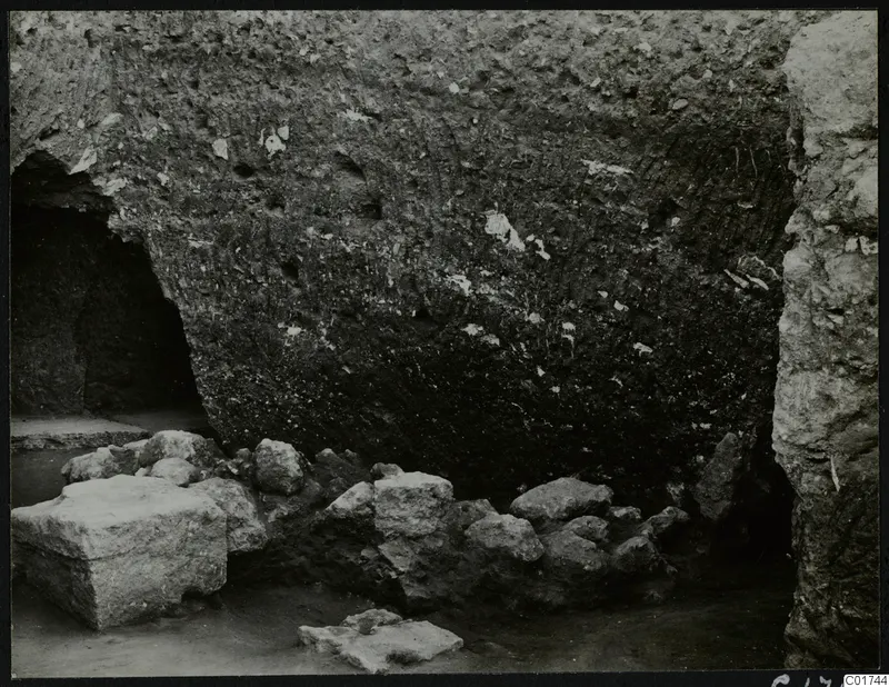 Soil section in the cult room at Kition, with a recess at left and stones and a cut block in front