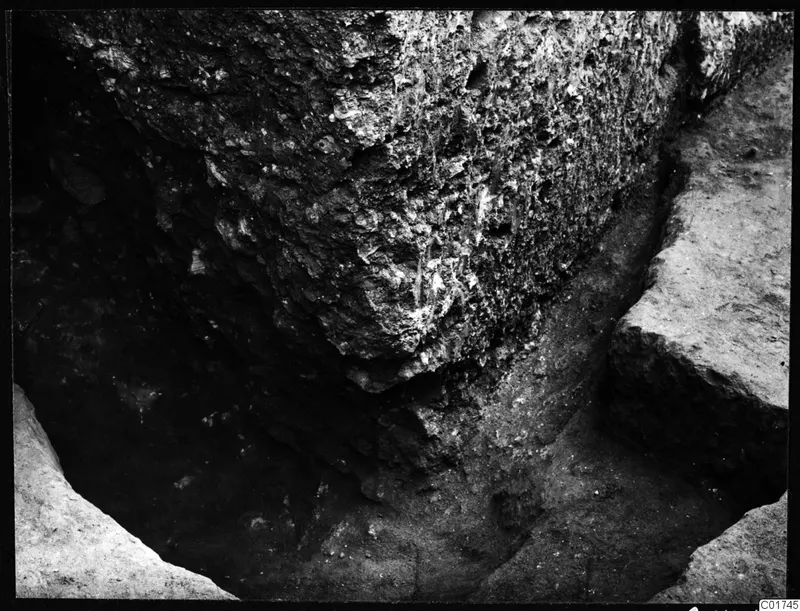 Rough stone face with soil and cut edges at the bottom of an excavation cutting at Kition