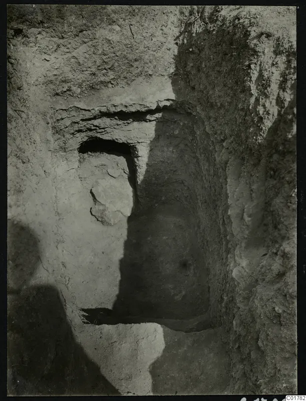 Tomb 7 at Kountoura Trachonia, seen from outside as a cut opening in a bank of earth with a stone block beside it