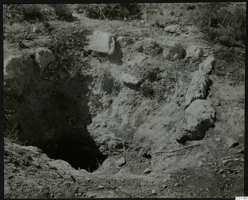 Excavation site at Kountoura Trachonia with a dark hollow in the ground and large stones around it