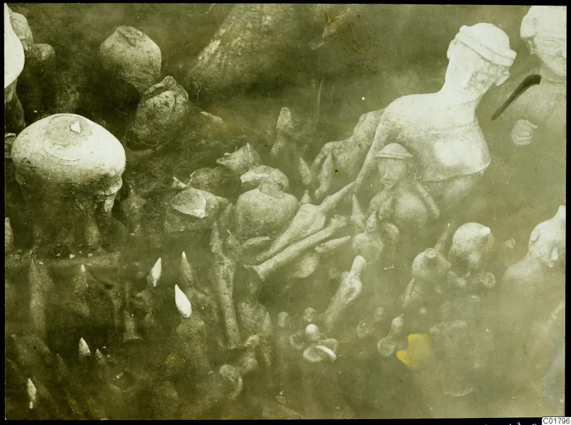 Statues, figurines and vessels photographed in situ in the soil during excavation at Ayia Irini