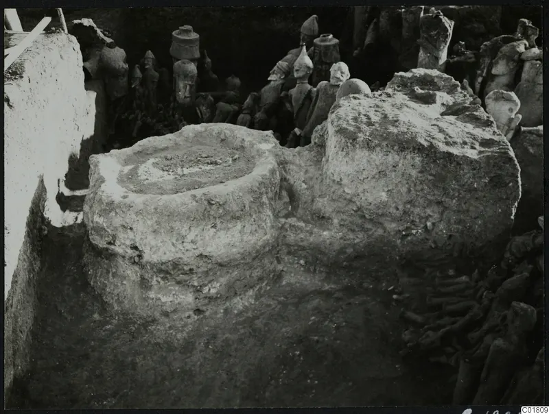 Terracotta figures found in situ in an excavation trench at Ayia Irini, beside a round stone basin.
