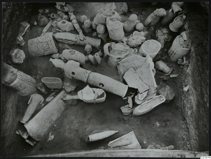 Excavation at Ayia Irini showing broken figure fragments and vessels lying in situ in the trench