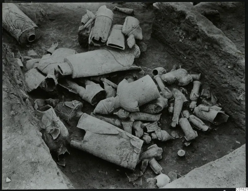 Excavated trench at Ayia Irini with many broken terracotta figurine fragments lying in the soil.