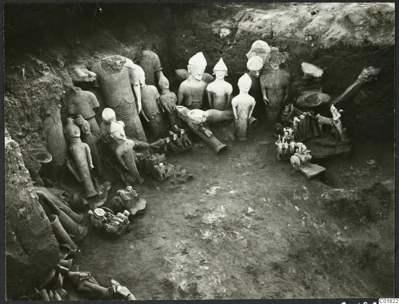 Statues and fragments found in situ in an excavation trench at Ayia Irini, pale figures among broken limbs and soil