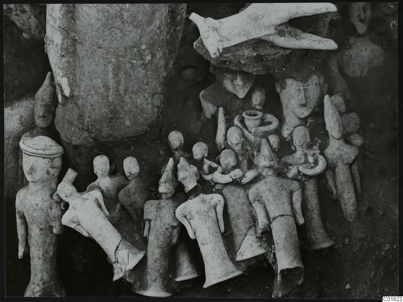Clay figurines and a bird-shaped object lying together in the soil at Ayia Irini, Square L 9-10.