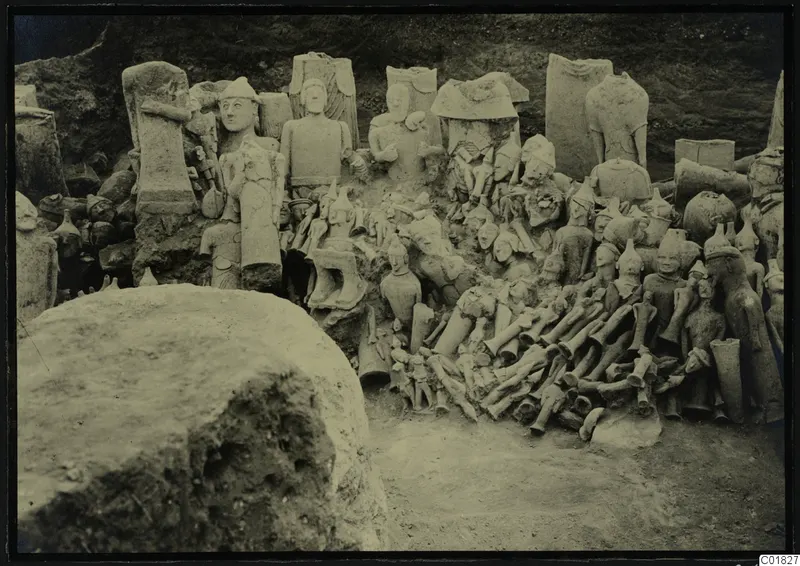 Field photograph of a votive deposit at Ayia Irini, western part, with many figures and fragments heaped against an earth bank