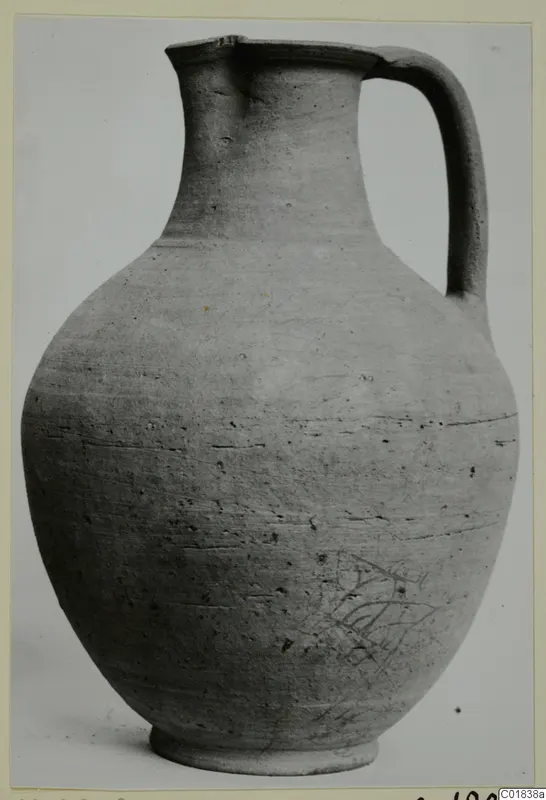 Pottery jug with a tall neck, single strap handle and rounded body, shown against a pale background.
