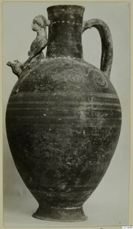 Bichrome-Red pottery jug with a modelled figure on the shoulder, photographed from the side