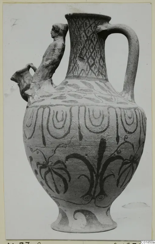 Pottery White Painted VII jug with a modelled human figure rising from the shoulder beside the spout