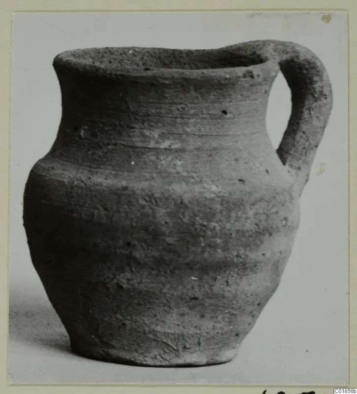 Plain pottery jug with a single handle, identified as Pottery Plain White VII from tombs 1–30