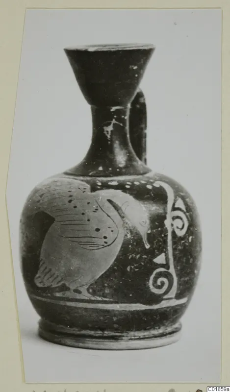 Small pottery jug with a bird and a spiral ornament painted on its body, photographed against a pale background