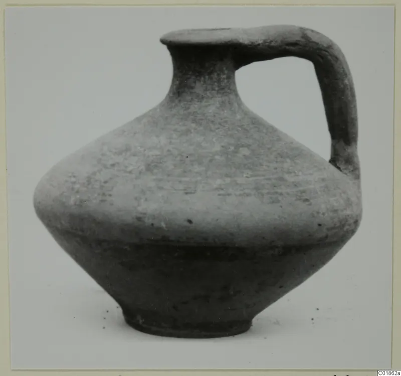 Black-slipped jug with a single loop handle, photographed against a plain grey background