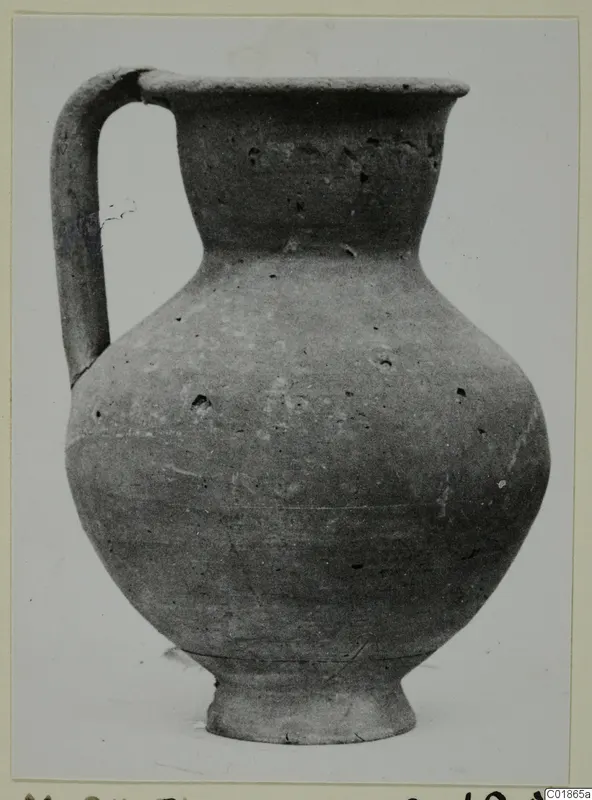 Plain pottery jug with a strap handle and wide rounded body, photographed against a pale background.