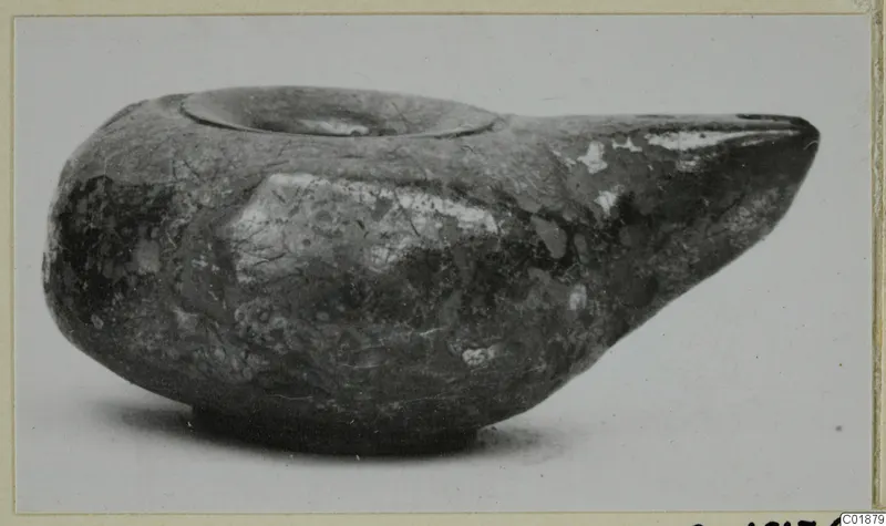 Black glazed lamp with a long pointed spout and a round filling hole, seen from the side.