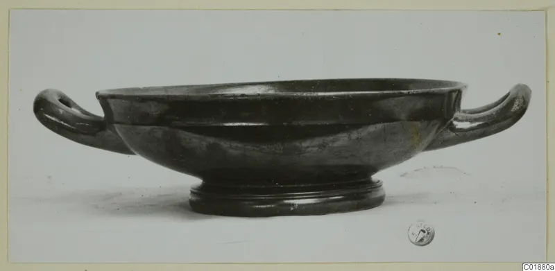Black glazed pottery bowl with two horizontal handles and a ring foot, from Marion tombs 31–45.