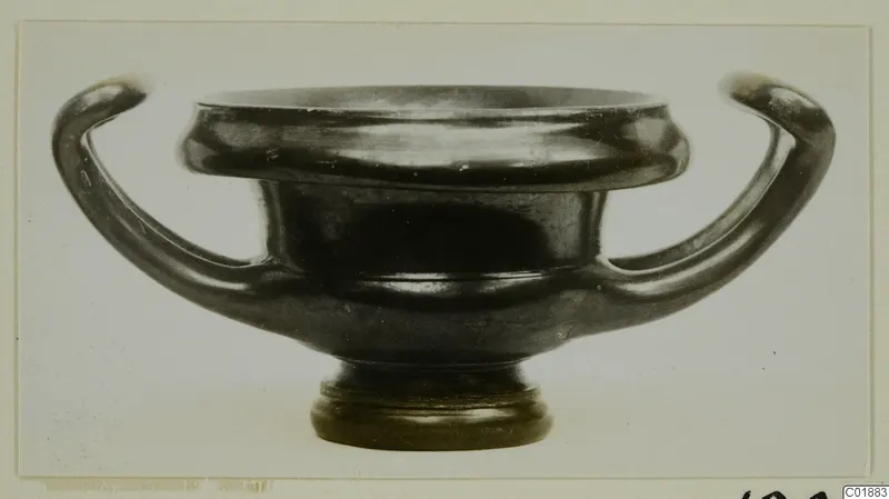 Black glazed two-handled vessel from Marion, seen from the side on a pale background