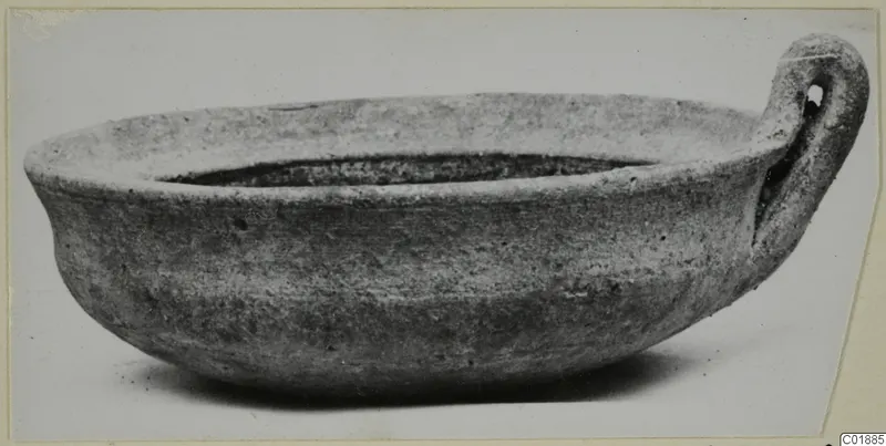Coarse ware bowl with a single loop handle, shown from the side against a pale background.