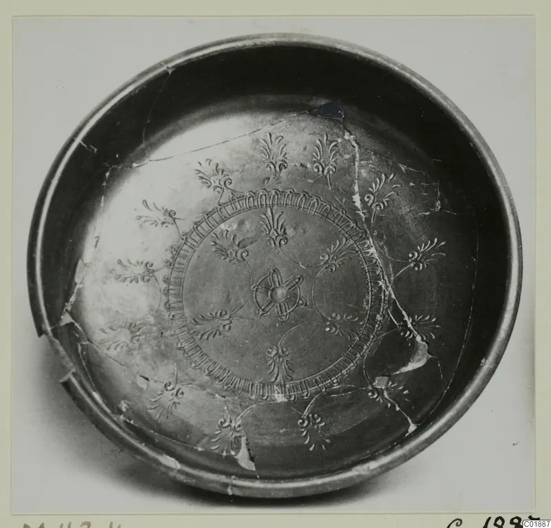 Black glazed bowl with rosette and palmette-like decoration inside, photographed from above