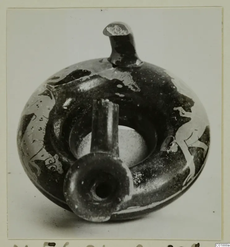 Dark-glazed vessel with a flat ring-like body, a tall upright spout and a short side spout, with pale painted figures on its sides.