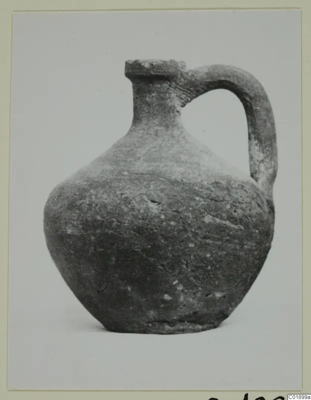 Single-handled pottery jug from the Marion tomb finds, photographed against a plain pale background.