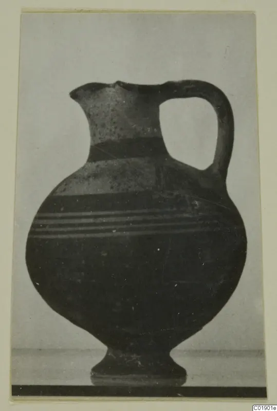 White Painted I jug with a high loop handle and a pedestal foot, photographed against a plain background