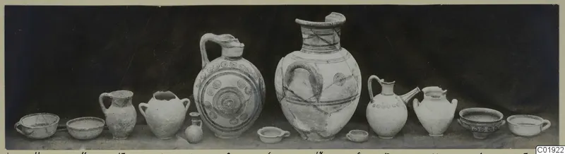 Jars and bowls from Marion, Dromos Niche, arranged in a row on a surface against a dark backdrop