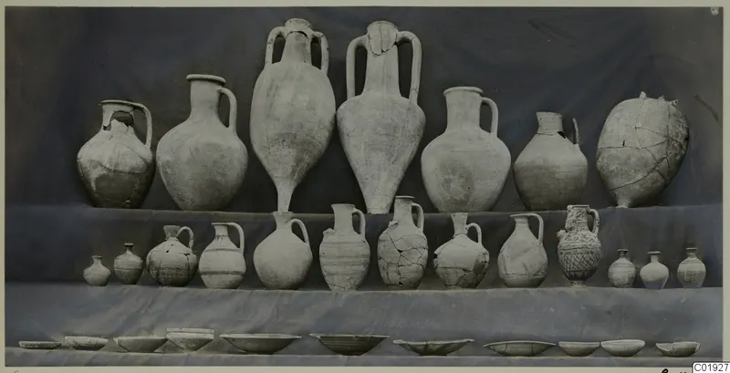 Pottery from Tomb 16 at Marion: jars, jugs and juglets set in tiers on draped cloth, with a row of bowls along the bottom.