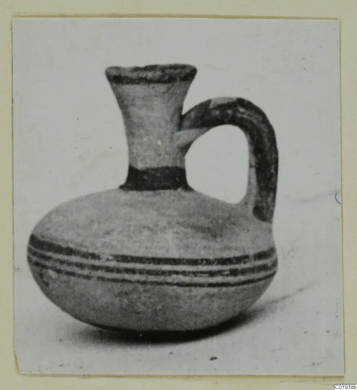 Small jug with a flaring neck, single loop handle and dark painted bands, photographed on a pale background.