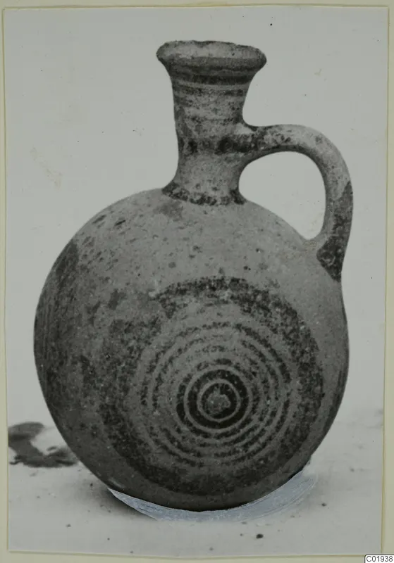 Pottery White Painted II juglet with a loop handle and dark concentric circles painted on its body