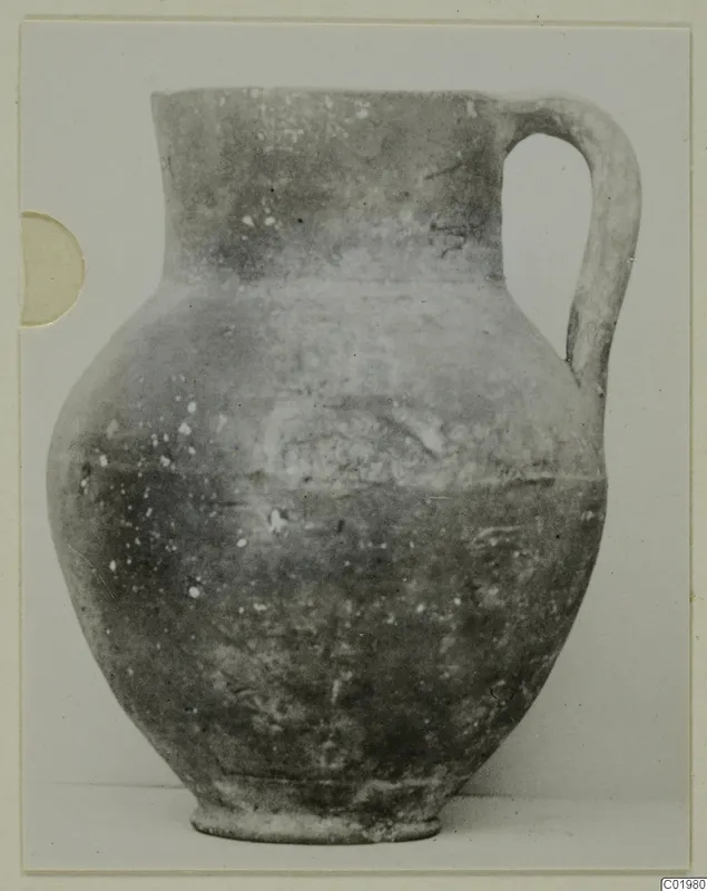 Coarse ware jug with a single handle, from the Kastros tombs at Lapithos, photographed against a plain background