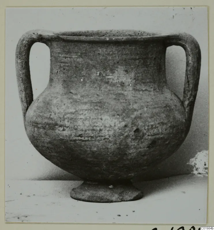Two-handled amphoriskos on a low foot, a pottery vessel photographed against a plain background.