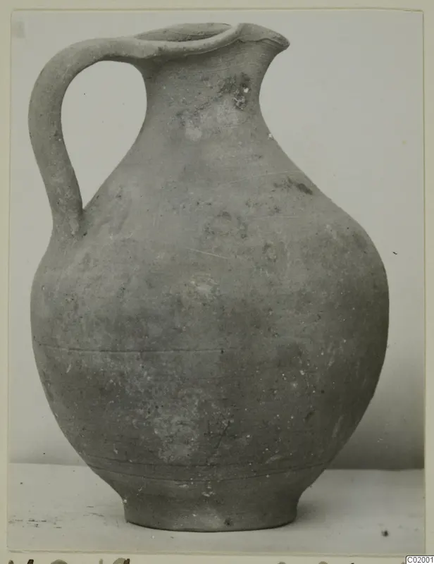 Pottery Plain White VII, a one-handled jug with a broken rim, photographed against a pale background