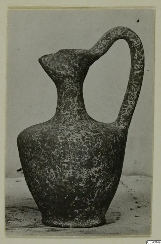 Pottery Plain White VI jug with a tall loop handle and a pointed spout, mottled dark surface