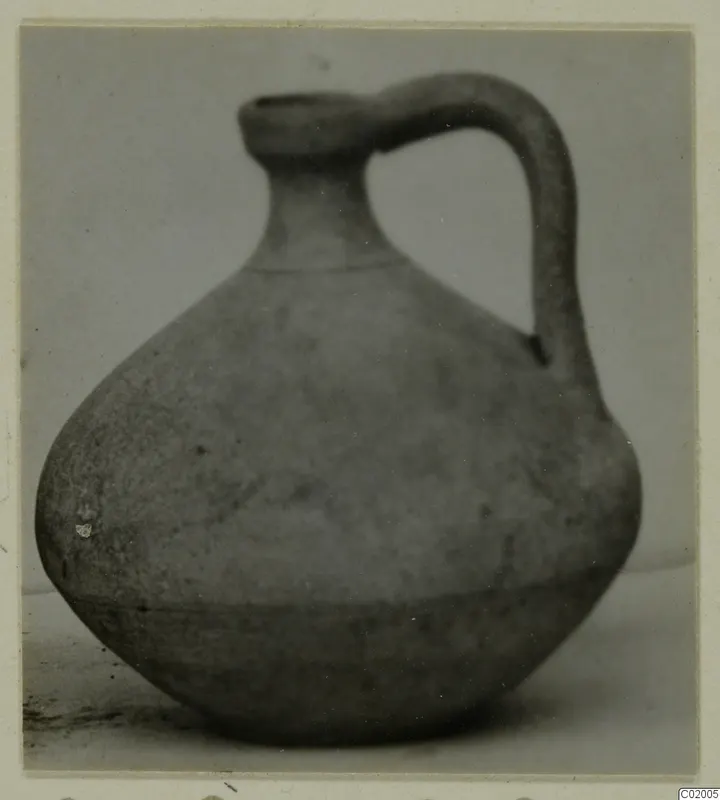 Pottery jug with a single loop handle and rounded body, photographed against a plain background.