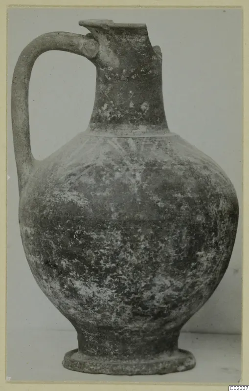Pottery jug with a loop handle, tall neck and ring foot, photographed against a plain background