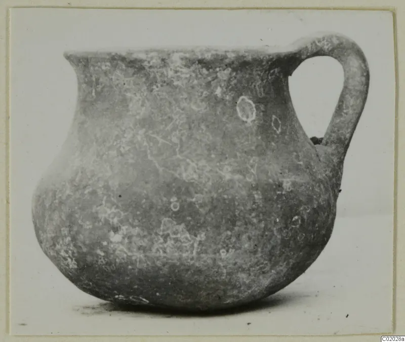 Pottery jar with a single loop handle and a rounded body, photographed against a plain background