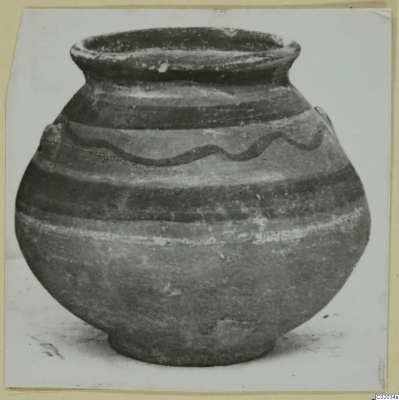 Round pottery vessel with a wide flaring rim and a dark wavy painted line around the shoulder
