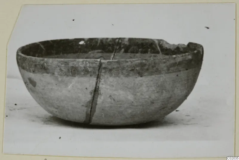 Pottery Bichrome IV bowl with a chipped rim and a long crack down its side, shown on a pale surface