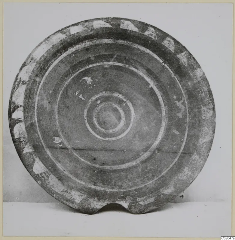 Round pottery vessel with a pale painted rim pattern and concentric circles at the centre, photographed face-on.