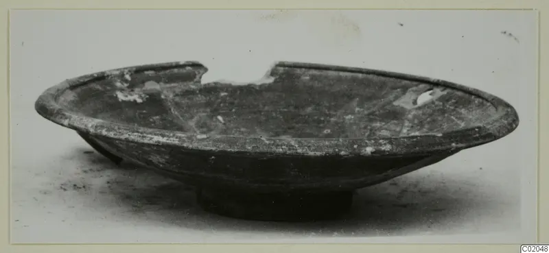 Shallow dark bowl with a broken rim and low ring foot, from Marion, shown in side view